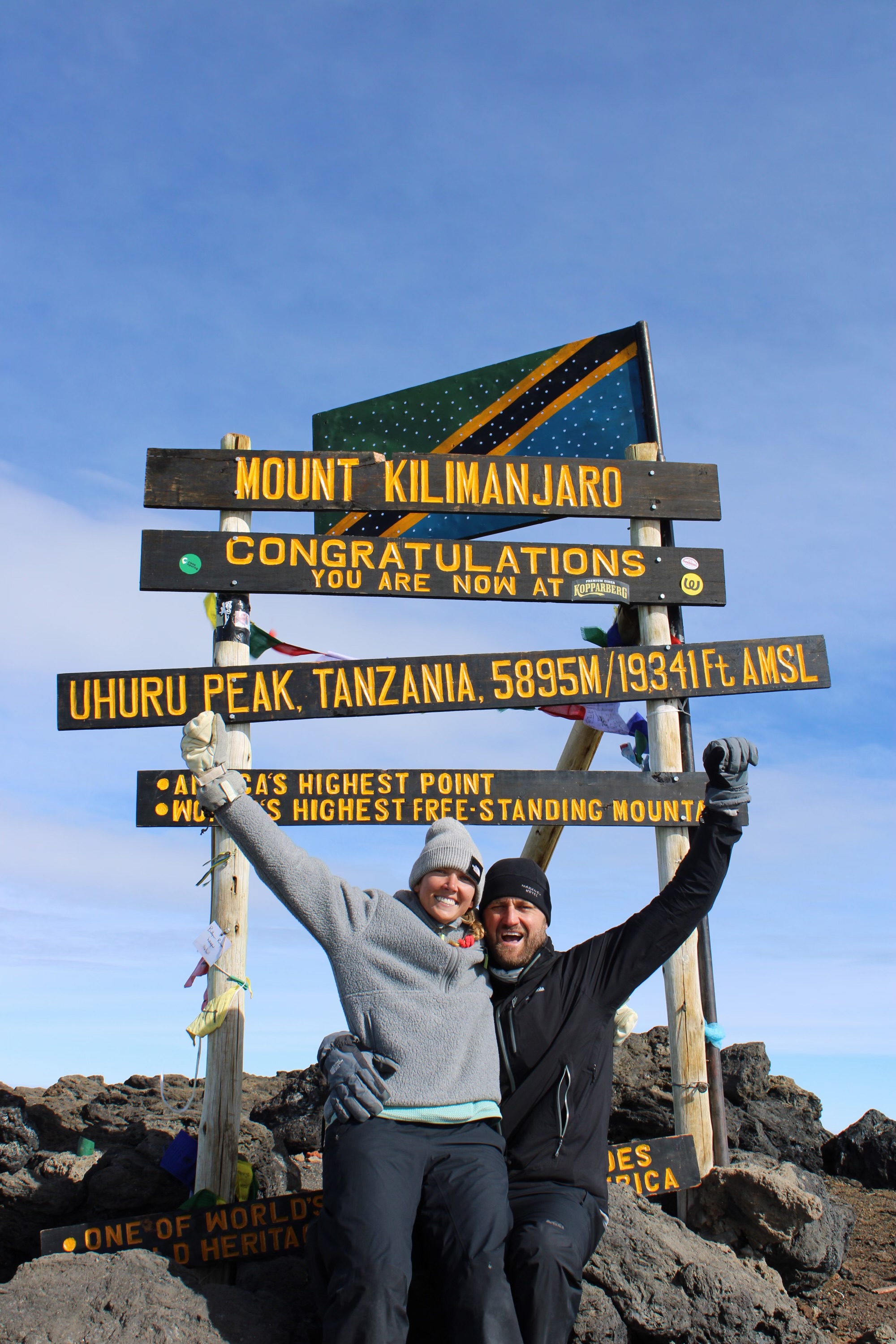 Celebrating at the Uhuru Peak sign on Mount Kilimanjaro, Tanzania