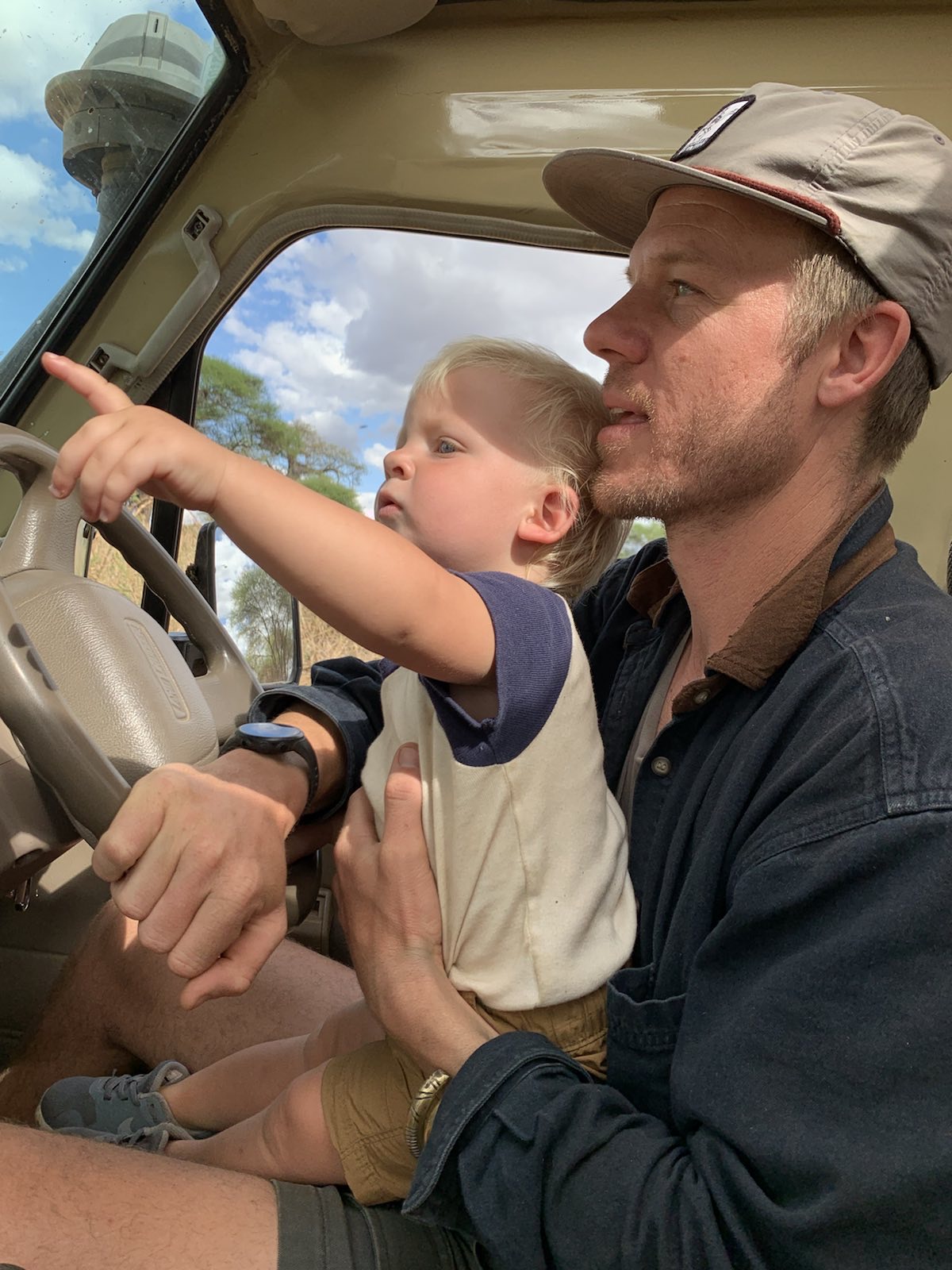 Trevor Borden with his young son in a safari vehicle in Tanzania, the boy pointing at wildlife