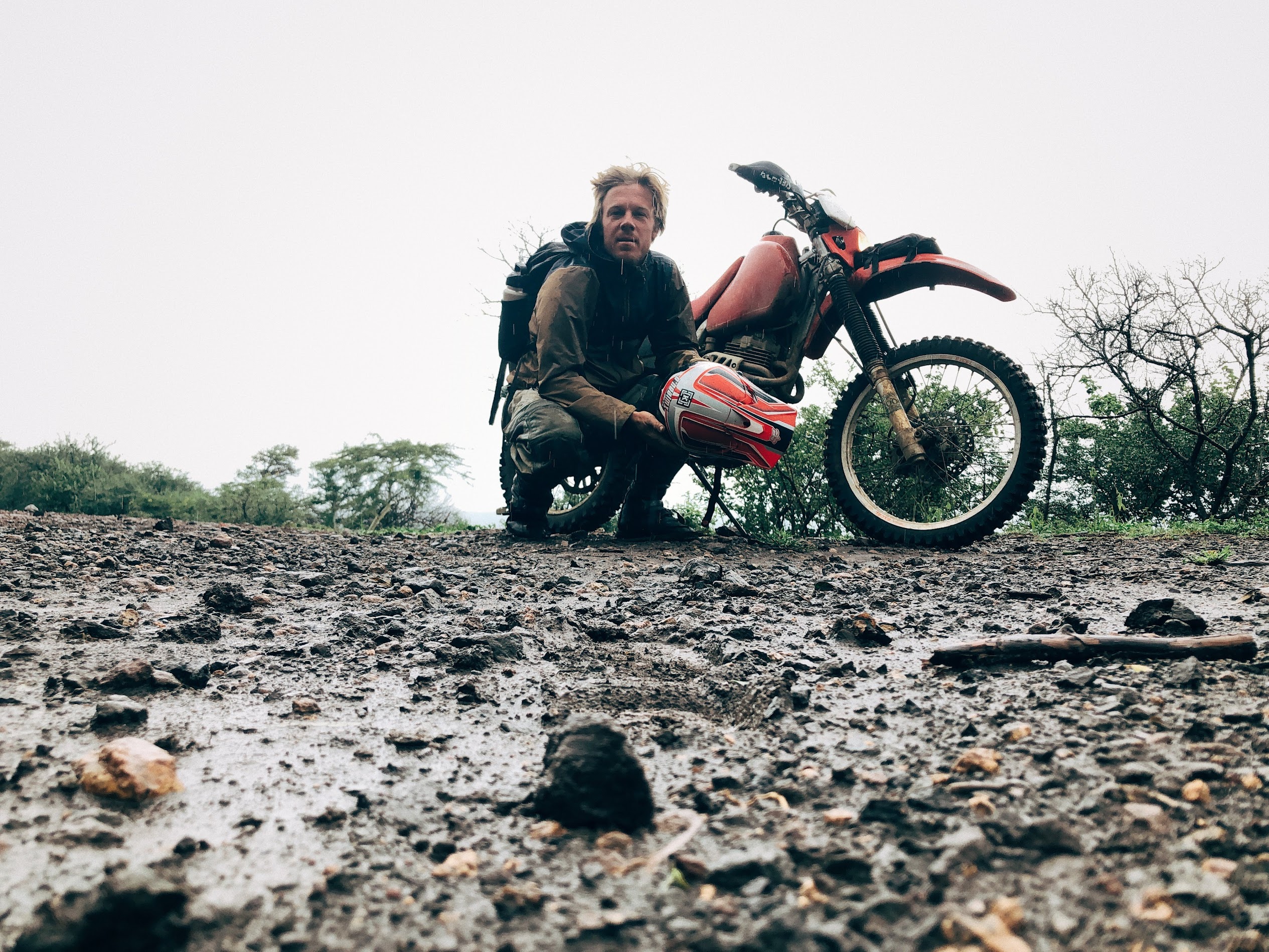 Trevor Borden beside his dirt motorcycle on a muddy, rocky track